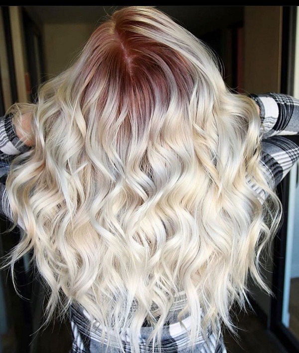 long wavy blonde hair with colored roots in a dark red shade